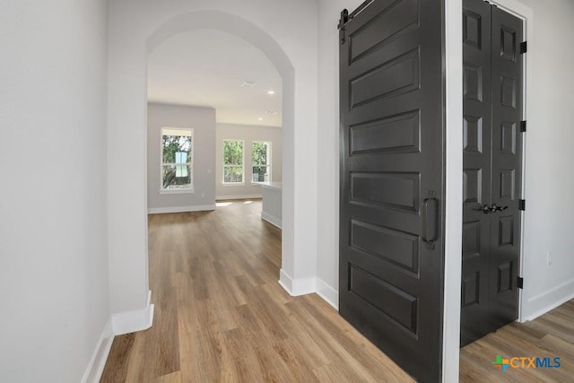 corridor featuring a barn door and hardwood / wood-style flooring