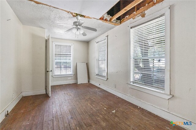 unfurnished room with a textured ceiling, dark wood-type flooring, and ceiling fan