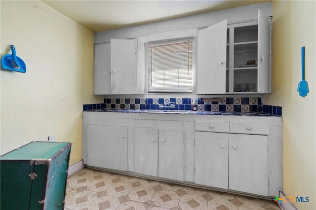 kitchen with white cabinetry, sink, and backsplash