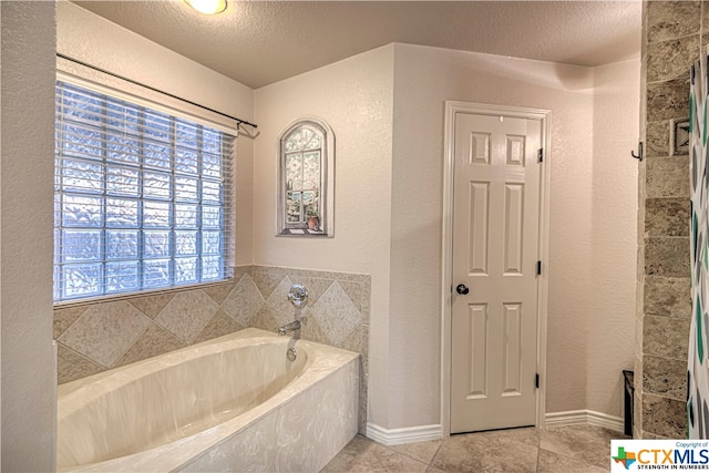 bathroom with a bath, a textured ceiling, and tile patterned floors