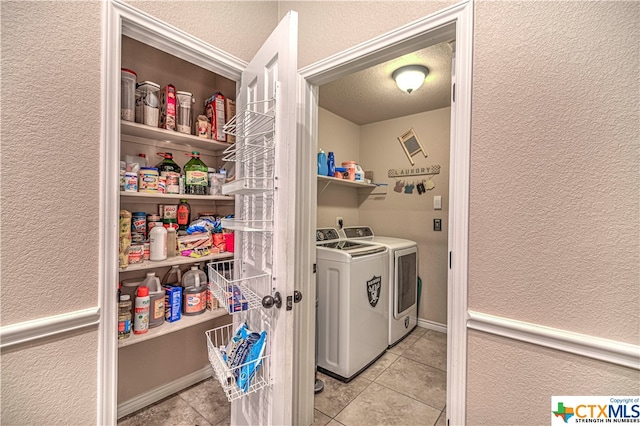 clothes washing area featuring separate washer and dryer, a textured ceiling, and light tile patterned floors