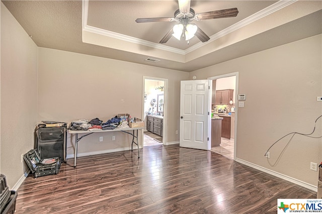 miscellaneous room with dark wood-type flooring, ceiling fan, ornamental molding, and a tray ceiling