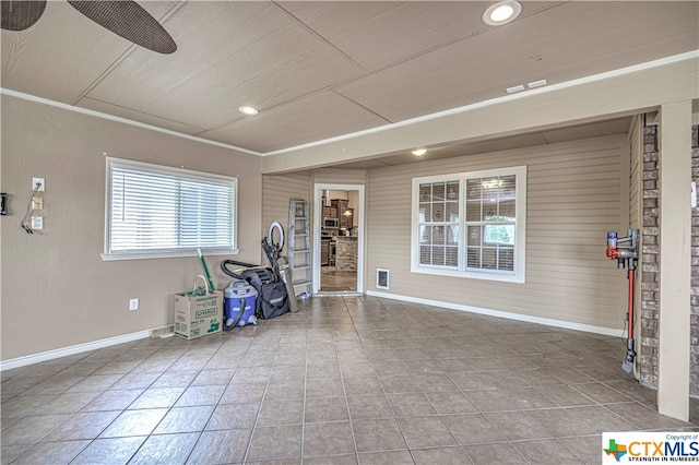 exercise room featuring tile patterned flooring, wooden walls, and ceiling fan