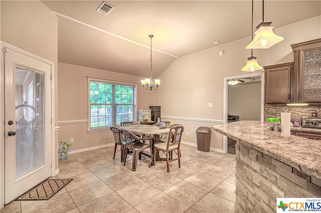 tiled dining space featuring vaulted ceiling and a notable chandelier