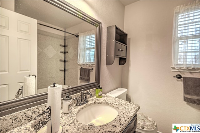 bathroom with toilet, a wealth of natural light, and tiled shower