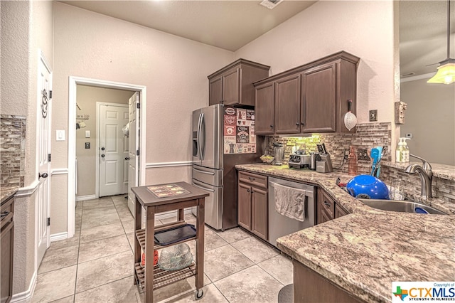 kitchen featuring sink, light stone counters, appliances with stainless steel finishes, and tasteful backsplash