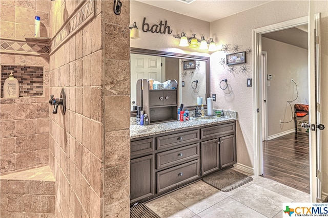 bathroom featuring tiled shower, vanity, and hardwood / wood-style flooring