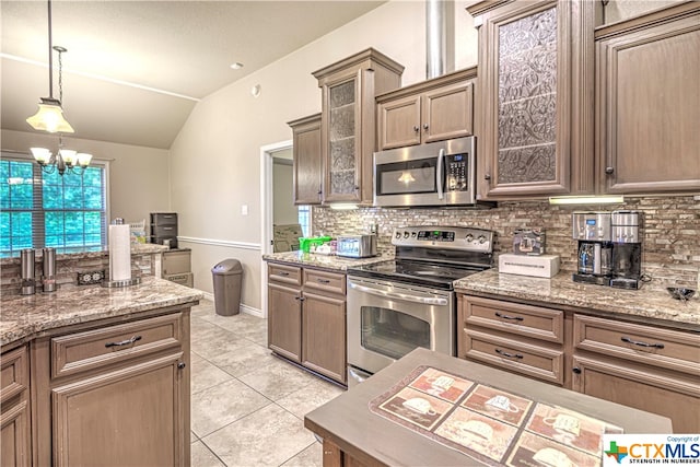 kitchen featuring lofted ceiling, a notable chandelier, tasteful backsplash, light stone countertops, and appliances with stainless steel finishes