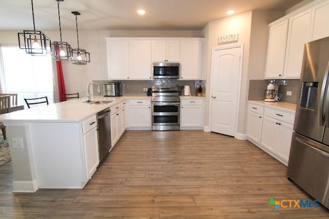 kitchen with stainless steel appliances, white cabinetry, pendant lighting, and kitchen peninsula