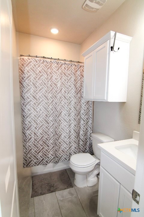 bathroom with a shower with curtain, tile patterned flooring, vanity, and toilet