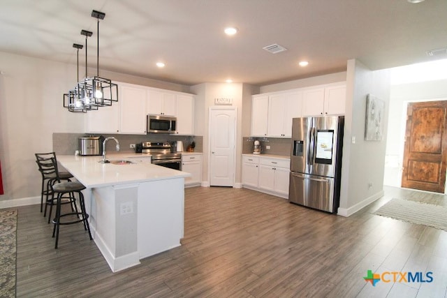 kitchen with pendant lighting, kitchen peninsula, appliances with stainless steel finishes, and white cabinets