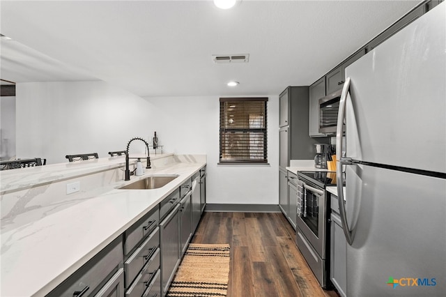 kitchen with visible vents, dark wood-style floors, stainless steel appliances, gray cabinetry, and a sink