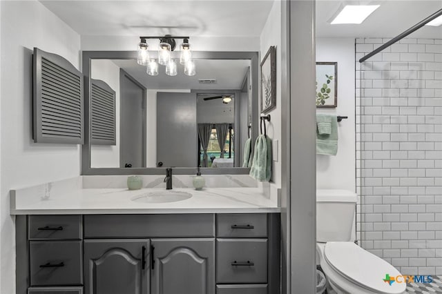 bathroom featuring visible vents, toilet, a tile shower, vanity, and ceiling fan