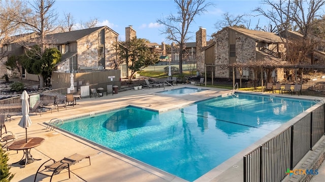 community pool featuring a patio area, fence, and a community hot tub