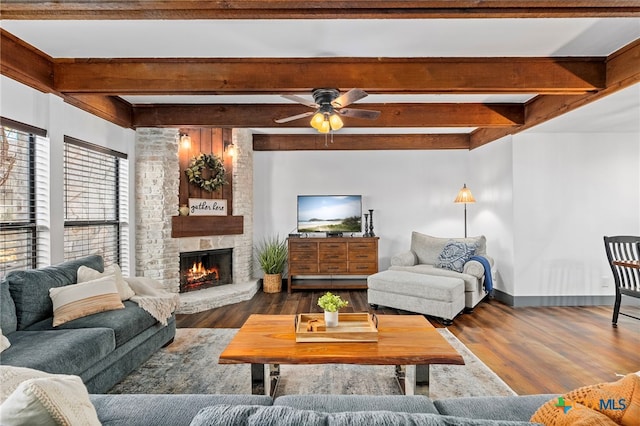 living room featuring dark wood-style floors, a fireplace, baseboards, and beamed ceiling