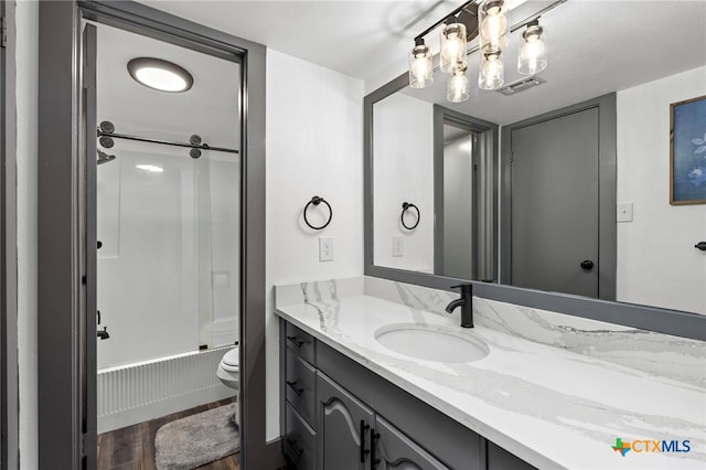 bathroom featuring bath / shower combo with glass door, wood finished floors, vanity, and toilet