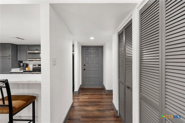 hall featuring visible vents, baseboards, dark wood-style flooring, and recessed lighting