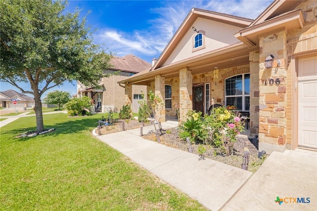 106 Sandstone Ct, Victoria, TX 77904 - property entrance featuring stone siding, a yard, a porch, and stucco siding