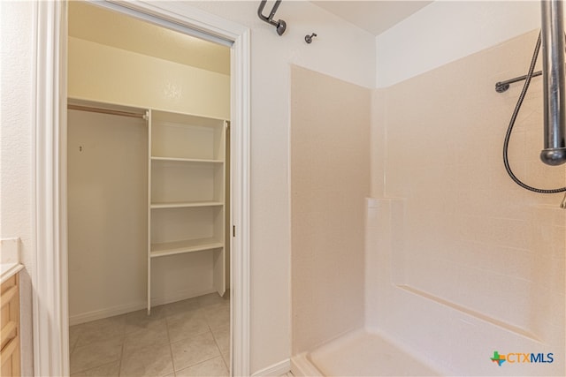 bathroom with tile patterned flooring, vanity, and a tile shower