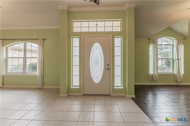 tiled foyer with ornamental molding and a healthy amount of sunlight