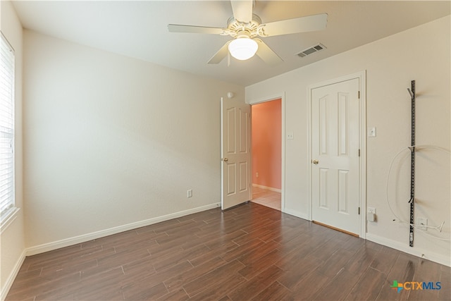 unfurnished bedroom featuring dark hardwood / wood-style floors, ceiling fan, and multiple windows