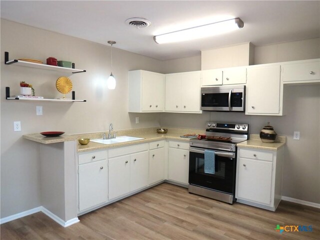 103 W Outer Dr, Canyon Lake, TX 78133 - kitchen with stainless steel appliances, a sink, light wood finished floors, and light countertops