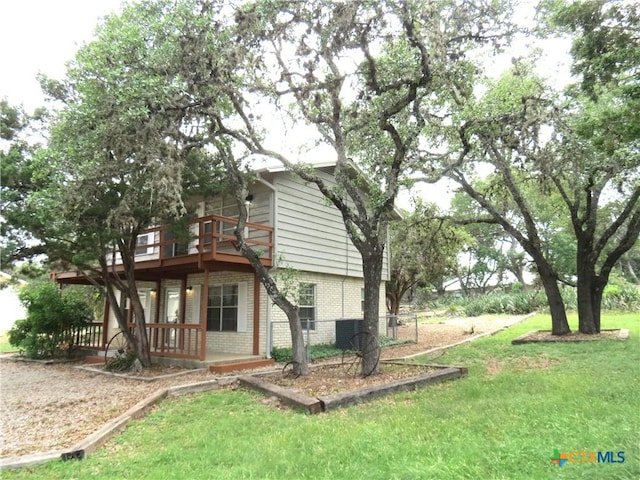 103 W Outer Dr, Canyon Lake, TX 78133 - view of home's exterior featuring brick siding, a lawn, central AC, and a balcony