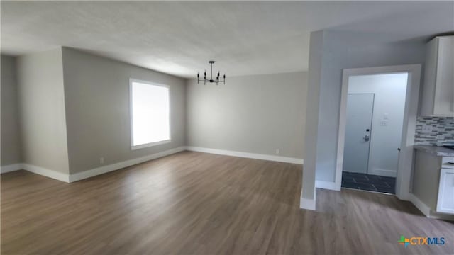 unfurnished dining area featuring baseboards, wood finished floors, and a chandelier