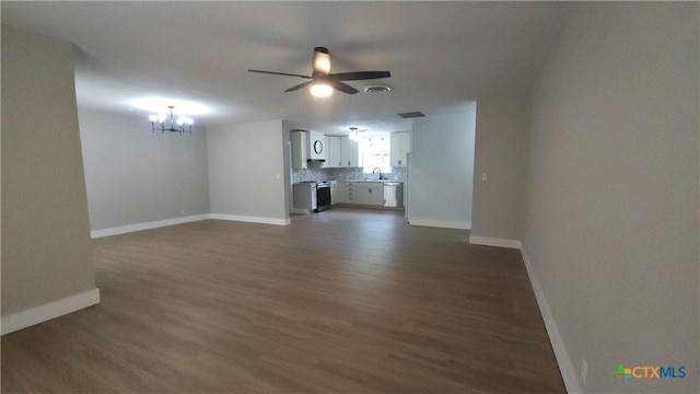 unfurnished living room featuring baseboards, dark wood-type flooring, and ceiling fan with notable chandelier