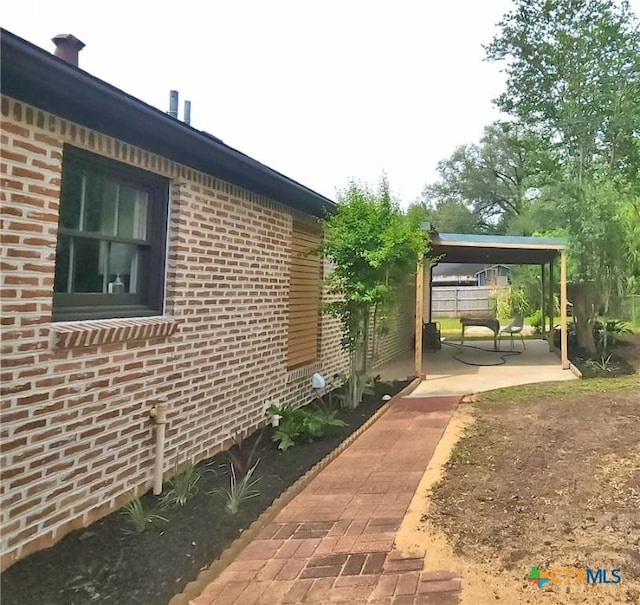 view of home's exterior with brick siding and a patio