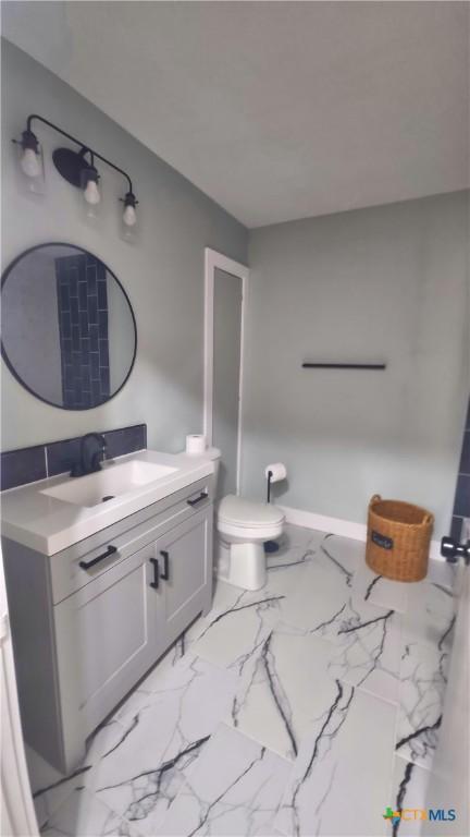 bathroom featuring marble finish floor, toilet, vanity, and baseboards