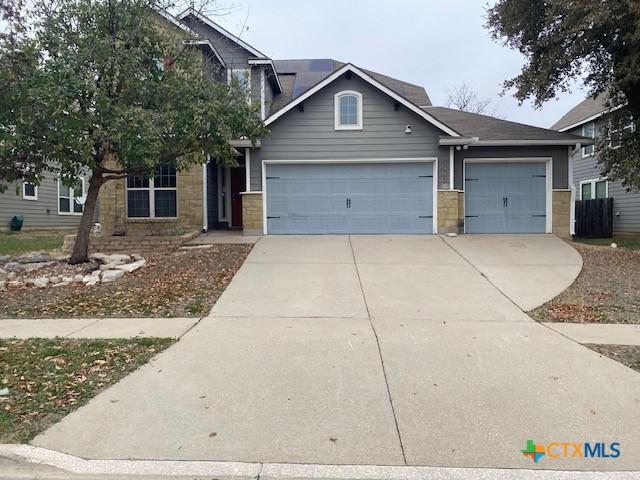 craftsman house featuring driveway, stone siding, and an attached garage