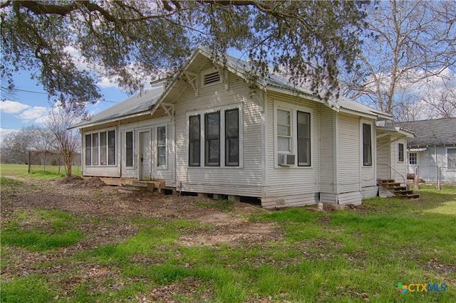 back of property featuring entry steps, a lawn, metal roof, and cooling unit