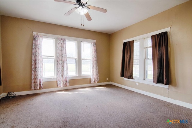 carpeted spare room with a ceiling fan and baseboards