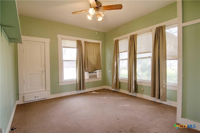 carpeted spare room featuring ceiling fan, baseboards, and cooling unit