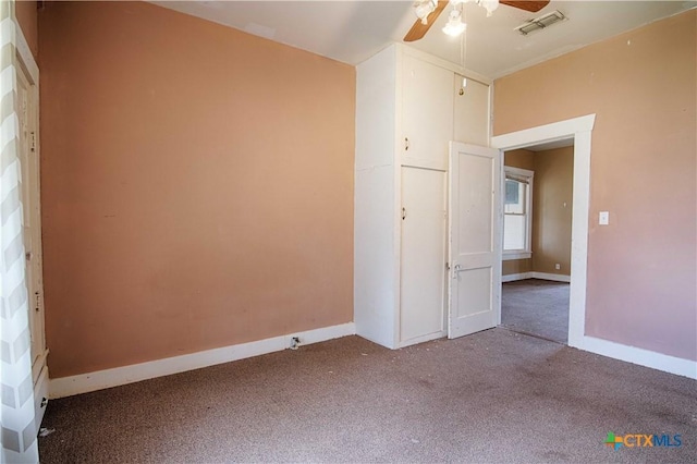 carpeted empty room featuring ceiling fan, visible vents, and baseboards