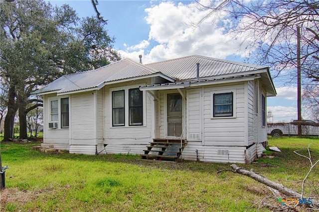 view of front of house with entry steps, metal roof, and a front yard