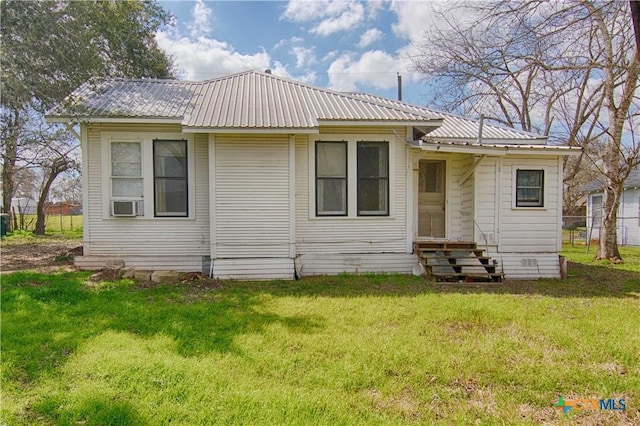 back of property with entry steps, metal roof, a lawn, and fence