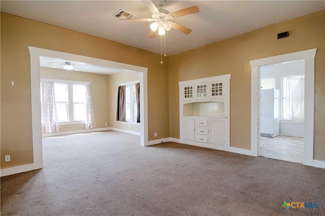 spare room featuring carpet floors, ceiling fan, visible vents, and baseboards