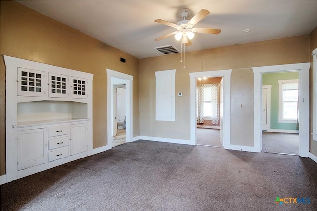 unfurnished bedroom with multiple windows, dark carpet, visible vents, and baseboards