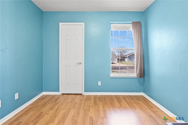 empty room featuring plenty of natural light, wood finished floors, and baseboards