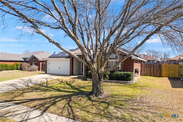 view of front of home with brick siding, solar panels, an attached garage, fence, and a front yard