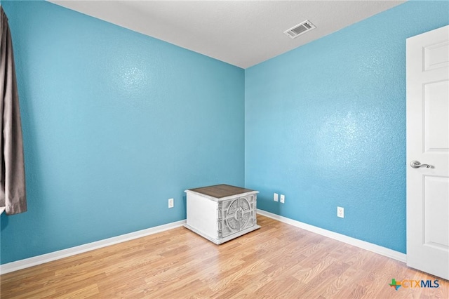 unfurnished room with baseboards, visible vents, and wood finished floors