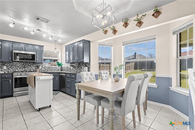 kitchen with light tile patterned floors, a kitchen island, visible vents, appliances with stainless steel finishes, and backsplash