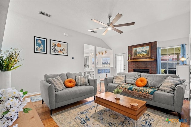 living area with a ceiling fan, visible vents, a fireplace, and light wood-style flooring