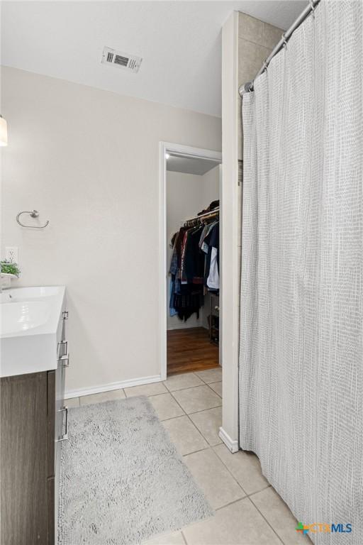 bathroom featuring visible vents, vanity, a shower with curtain, baseboards, and tile patterned floors