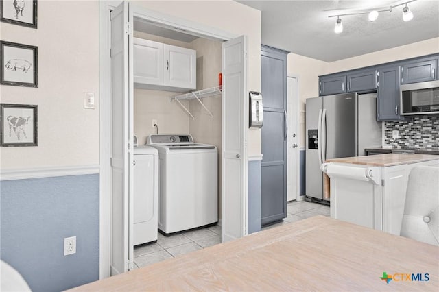 kitchen with light tile patterned floors, light countertops, decorative backsplash, appliances with stainless steel finishes, and washing machine and dryer