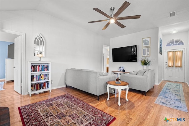 living area featuring visible vents, a ceiling fan, vaulted ceiling, wood finished floors, and baseboards