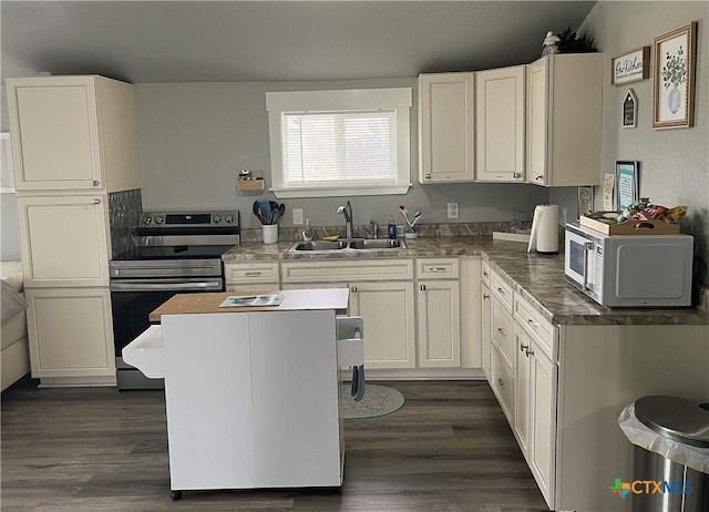 kitchen featuring electric stove, white microwave, white cabinets, a kitchen island, and a sink