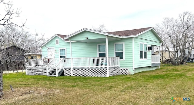 rear view of house featuring roof with shingles and a lawn